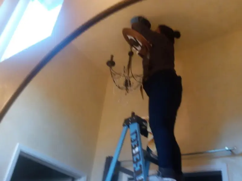 Electrician installing a chandelier in a Middletown residence